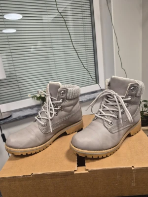 Gråa stövletter med stickad kant från Duffy 36 - Snygga gråa stövletter med snörning och grov sula. Ovandelen är i matt skinnimitation och skaftet har en stickad, ljusgrå kant upptill som ger en cool kontrast. Perfekta för dig som vill ha både stil och edge i höst och vinter.