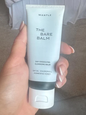 Mantle The Bare Balm rengöringsbalm - The Bare Balm från Mantle är en dag-dissolving cleansing balm med havreolja, klorofyll och fermenterad honung. Tuben är vit med svart detalj och har praktisk flip-top. Perfekt för att smälta bort smink och rengöra huden på djupet.