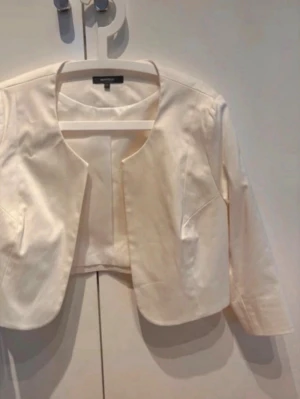 Montego kavajett, stl 44 - Elegant, crémefärgad kavajett med 3/4-ärmar av märket Montego.  Använt endast en gång på bröllop.   97 % bomull och 3 % elastan.  Liten fläck på vänster sida baktill, men kan säkerligen behandlas.  Djur- och rökfritt hem.