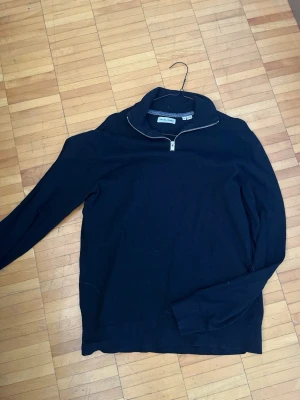 Svart halfzip från Jack & Jones  - Svart stickad tröja från Jack & Jones med hög krage och dragkedja framtill. Tröjan har långa ärmar och ribbade muddar vid ärmslut och nederkant. Perfekt för lager-på-lager och stilren look.