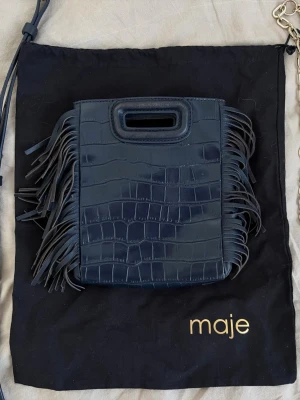 Blå Maje-väska! - Mörkblå handväska från Maje i crocoliknande skinn med fransar på sidorna. Väskan har ett handtag och medföljande axelrem + kedja med gulddetaljer. Sparsamt använd, nypris ca 3.000kr. 