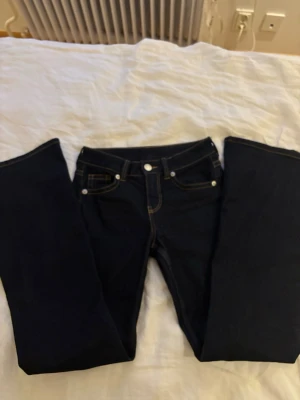 Mörkblå bootcut jeans med kontrastsömmar - Snygga mörkblå bootcut jeans med tydliga kontrastsömmar och klassisk femficksdesign. 