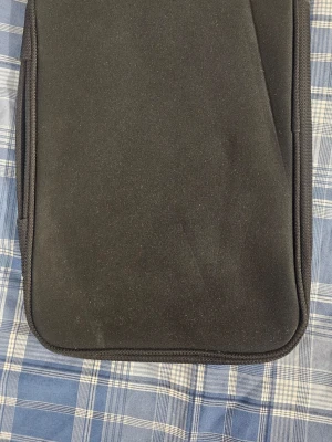 Svart datorfodral från Belkin - En stilren svart datorväska från Belkin i mjukt material. Fodralet har en enkel, rektangulär form och dragkedja längs kanten. Perfekt för att skydda din laptop på språng och passar till de flesta standardstorlekar.