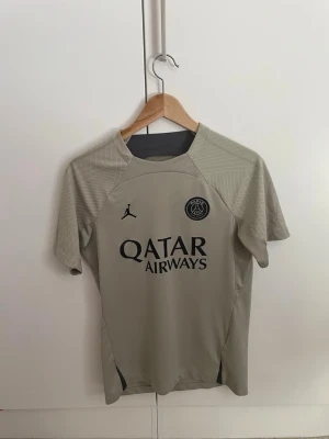  PSG matchtröja - Snygg beige PSG matchtröja från Jordan med svart logga och passar perfekt till träning, skolan eller match. Använd kanske 5-7 gånger men gillar fan inte PSG. Den är i storlek M men passar perfekt i s också (har de själv)!