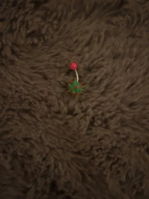 Piercingsmycke med grön taggboll - Unikt piercingsmycke med en grön och röd taggig boll i silikon och en rosa kula upptill. Böjd stav i metall. Perfekt för dig som vill ha något färgglatt och lekfullt i din piercing.