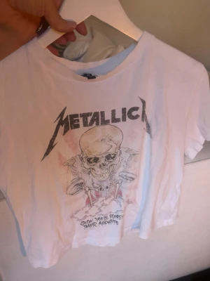 Vit Metallica t-shirt från H&M Divided - Vit t-shirt från H&M Divided med Metallica-tryck framtill. T-shirten är väldigt mjuk och tunn