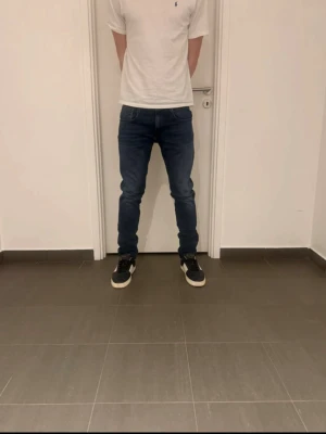 Mörkblå slim fit jeans herr - Säljer ett par mörkblå slim fit jeans med klassisk femficksdesign och normal midja. Jeansen har en snygg tvätt och smal passform som sitter tajt längs benen. Perfekta till sneakers och t-shirt för en clean look.