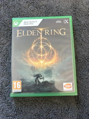 Elden Ring Xbox Series X/Xbox One - Elden Ring till Xbox Series X och Xbox One. Spelet kommer i ett grönt plastfodral med omslag i svart och guld, och innehåller både spel-skiva och bonuskod. Omslaget har fantasyinspirerad konst.