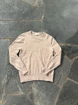 Beige stickad tröja Sayless - Snygg beige stickad tröja från Sayless i mjuk och tunn kvalitet. Tröjan har rund halsringning, långa ärmar och ribbade muddar vid ärmslut och nederkant. Perfekt basplagg för lager på lager och enkel att matcha.