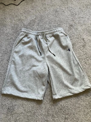 Shorts Ralph Lauren - Gråa Ralph Lauren shorts med elastisk midja och snörning. Shortsen är använda ett fåtal gånger. Vid frågor så bara hör av dig, priset kan diskuteras 