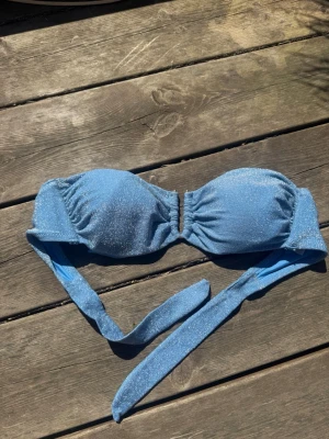 Blå glittrig bandeau bikiniöverdel - Snygg blå bandeau bikiniöverdel med glittrigt tyg🙌🏽💙Storlek m men passar fler storlekar då man kan sjustera banden hur man vill ha den! Har även en matchande underdel i stl S vid intresse som ingår💙