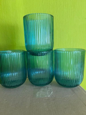 Gröna räfflade glas, 4-pack - Fyra snygga dricksglas i grönt glas med räfflad yta och rundad form. Perfekta för vatten, juice eller läsk. Glasen har en modern look och passar bra i köket eller till middagsbordet.