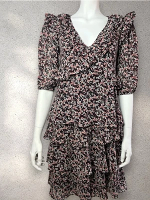 Blommigt set med blus och kjol med volanger och V-ringning. - Supersöt kort blommig set med volanger och v-ringning. Klänningen har puffiga trekvartsärmar och ett svart tyg med små vita och rosa blommor. Perfekt för dig som gillar romantisk och trendig stil. #michaelkors PS: blus stollek XS, kjol stolek: S