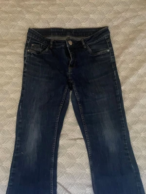 Mörkblå raka jeans - Säljer ett par mörkblå jeans med raka ben och klassisk femficksdesign. Jeansen har snygga slitningar framtill och kontrastsömmar. Perfekta till en avslappnad stil och passar till det mesta. Materialet är denim i bomull.