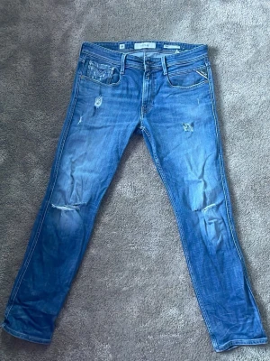 Replay jeans - Säljer ett par blå jeans från Replay i modellen Anbass. Skick är 8/10 med snygga slitningar. Vid fundering är det bara att fråga🍀