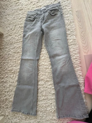 Grå bootcut jeans  - Säljer ett par grå jeans med bootcut-modell och utsvängda ben. Klassisk femficksdesign och normal midja. Perfekta för dig som gillar en avslappnad och trendig stil. Materialet är denim i bomull.