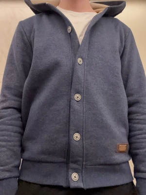 Cardigan med knappar  - Mörkblå cardigan med knappar och luva. Tröjan är i mycket bra skick. Ruggit soft tröja som funkar till det mesta. Tröjan är i storlek S. Pris kan diskuteras!