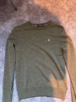 Olivgrön tröja från Morris - Snygg olivgrön tröja från Morris med rund halsringning och diskret broderad logga på bröstet. Tillverkad i mjukt material som känns skönt mot huden. 