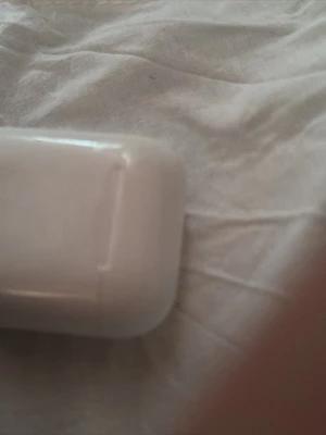 Vit trådlös hörlurslåda - Säljer ett vitt fodral till trådlösa in-ear hörlurar. Fodralet är kompakt och har rundade kanter, perfekt för att ladda och förvara hörlurarna. Passar smidigt i fickan och har en stilren design i plast.