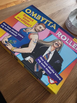 Ombytta Roller sällskapsspel - Säljer sällskapsspelet Ombytta Roller, ett roligt och avslöjande spel där man får testa hur man klarar sig som det motsatta könet. Spelet har färgglad kartong med illustrationer och innehåller spelplan, kort och spelpjäser. Fint skick, komplett med spelregler. 
