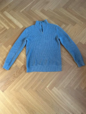 Grå half zip tröja från Qubus - Säljer en stilren grå stickad tröja med halvzip och hög krage från Qubus!🔥 Vanlig passform och look som funkar för alla årstider!👌🧊Perfekt att bära över en skjorta för en snygg lager-på-lager-look men kan också stylas lätt med en t-shirt. Hör av er vid minsta fundering!📌😎