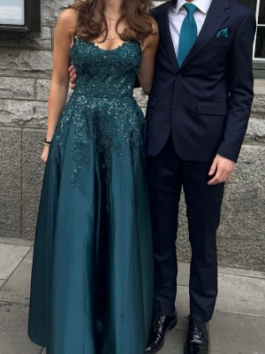 Mörkgrön långklänning med spetsdetaljer - Säljer min balklänning, jätte fin och finns över matchande slips & näsduk om ni vill köpa med det. I priset ingår endast priset för klänningen, om slips och näsduk också önskar är det 300kr extra, eller om ni vill köpa slips och näsduk separat från klänningen.