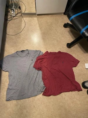 Två t-shirts från Polo Ralph Lauren - Säljer två klassiska t-shirts från Polo Ralph Lauren. Ena är grå och den andra vinröd, båda med den ikoniska lilla loggan broderad på bröstet. T-shirtsen har rund halsringning och korta ärmar. Perfekta basplagg i mjuk bomull.