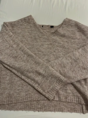 Beige stickad tröja med v-ringning - Mysig beige stickad tröja från H&M med v-ringad hals och långa ärmar. Tröjan har en avslappnad passform och ribbstickade detaljer vid ärmslut och nederkant. Perfekt för lager-på-lager och chill dagar.