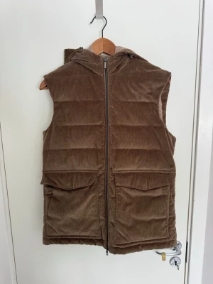 Brun Stenströms väst - Snygg brun dunväst i manchestertyg med dragkedja framtill och två stora fickor. Västen har en mysig huva och quiltad design som ger extra värme. Normal i storleken! Tveka inte på att fråga!  