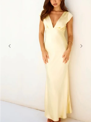 Ljusgul maxiklänning med v-ringning - Säljer en elegant ljusgul maxiklänning med djup v-ringning och korta ärmar. Klänningen har aldrig använts och har prislappen kvar.