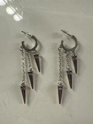 Silvriga örhängen med kedjor och spikes - Säljer ett par silvriga örhängen med kedjor och piggar. Aldrig använda