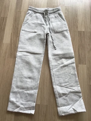 Grå mjukisbyxor från Lager 157, stl XS - Säljer ett par ljusgrå mjukisbyxor med raka ben och bred resår i midjan. Byxorna har snörning och två stora fickor framtill. Sparsamt använda, så i bra skick. Storlek XS. Just nu fri frakt, så du betalar bara för byxan. Jag har fler plagg ute, och hittar du något mer från min garderobsutrensning, så skickar jag allt i samma paket.