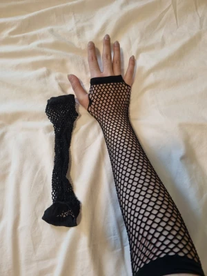 Svarta fishnetärmar - Fishnet fingerlösa ärmar eller handskar eller vad det nu är. Insåg att jag knappt rörde dem. Når upp till armbågarna.
