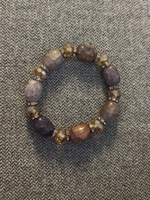 Armband med stora pärlor - Snyggt armband med stora, multifärgade pärlor i bruna, lila och beige nyanser. Mellan pärlorna sitter mindre, facetterade guldfärgade pärlor och glittriga detaljer. Perfekt accessoar för att lyfta din outfit med lite extra bling. Köpt på en secondhand butik men i väldigt bra skick