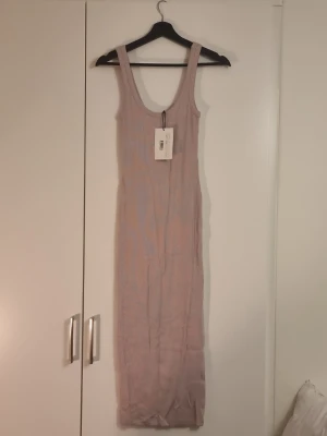 Lång ribbad klänning Ivyrevel - Lång ribbad klänning i en mjuk, ljuslila nyans från Ivyrevel. Klänningen är ärmlös med breda axelband och har en kroppsnära passform. Perfekt för dig som gillar minimalistisk och stilren design.