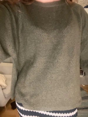 Grön stickad t-shirt - En enkel och snygg olivgrön stickad tröja med rund hals och korta ärmar. Tröjan har en rak passform och är gjord i mjukt stickat material som känns skönt mot huden. Perfekt att slänga på sig när det är kyligt ute.