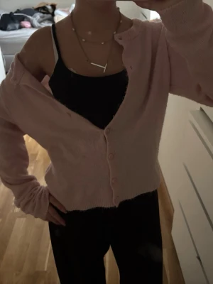 Ljusrosa kofta med knappar - Söt ljusrosa kofta med rund halsringning. Koftan har långa ärmar och sju matchande knappar framtill. Passar perfekt till lager på lager och ger en mjuk, trendig look.