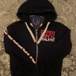 Vintage Superdry Hoodie  - Säljer min mörkblåa vintage superdry hoodie. Riktigt hög och tjock kvalité som håller dig varm. Inga direkta defekter, storlek S, passar dig bäst mellan 170-180. 
