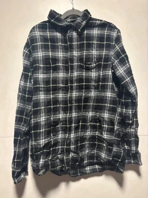 Svartvit rutig skjorta - Klassisk svartvit rutig skjorta med knappar framtill och två bröstfickor. Skjortan har lång ärm och en avslappnad passform, perfekt för en chill och stilren look. Tillverkad i mjuk bomull som känns skön mot huden. Från h&m i storlek M