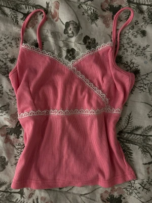 Rosa ribbad linnetopp med spets - Söt rosa ribbad linnetopp som funkar både som linne hemma men också kan stila den till en outfit. Perfekt för en trendig och feminin look.