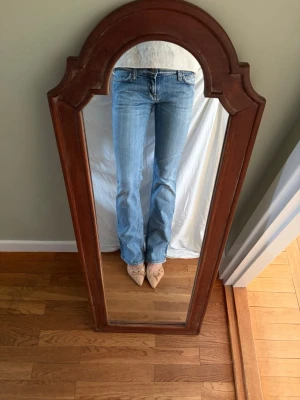 Ljusblå bootcut jeans med låg midja - Säljer ett par ljusblå bootcut jeans från Meltin’ Pot med låg midja. Jeansen har snygga kontrastsömmar och lätt slitna detaljer vid bensluten. W29/L34. 98% bomull.