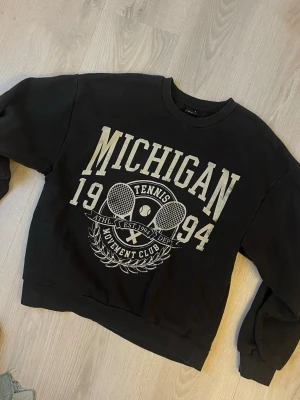 Svart Michigan sweatshirt från Ginatricot - Cool svart sweatshirt från Ginatricot med stort tryck framtill. Pris kan alltid diskuteras 💕