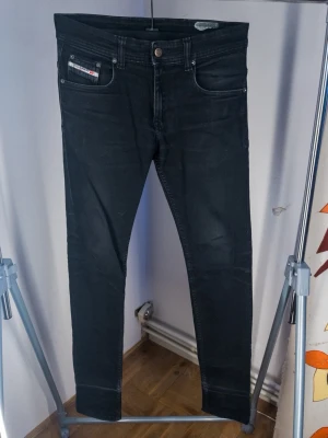 Svarta skinny jeans från Diesel - Snygga svarta skinny jeans från Diesel med klassisk femficksdesign och silverfärgade nitar. Jeansen har en smal passform och är tillverkade i stretchigt denim för extra komfort. Perfekta för en trendig och avslappnad stil.