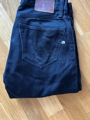 Svarta Edwin jeans - Säljer ett par svarta jeans från Edwin med klassisk femficksdesign och tydlig bakficka med den ikoniska sömmen. Jeansen har en rak passform och är tillverkade i slitstarkt bomullsmaterial. Perfekta för dig som gillar tidlös stil.