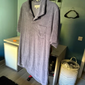 Blå frottéskjorta från Studios M - Mjuk och chill blå skjorta från Studios i frottématerial. Har en bred krage, korta ärmar och en bröstficka som ger en avslappnad vibe. Perfekt för dig som gillar oversized känsla och vill sticka ut med något annorlunda.