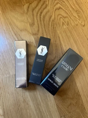 YSL L'Homme & Armani Code parfym - Säljer tre oöppnade herrparfymer: två YSL L'Homme Eau de Toilette i e bruna och svarta förpackningar samt en Armani Code Eau de Toilette från Giorgio Armani i svart box. Perfekt för dig som vill ha en lyxig och modern doft.