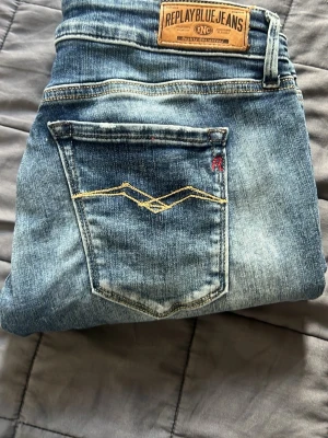 Replay blå jeans med kontrastsömmar - Snygga blå jeans från Replay med klassisk femficksdesign och kontrastsömmar på bakfickan. Jeansen har en ljus tvätt och raka ben, samt läderpatch med logga bak. Perfekta för dig som gillar en avslappnad och trendig look.    Pris kan diskuteras