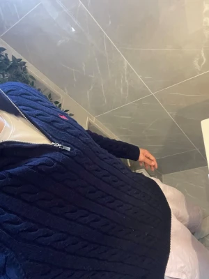 Mörkblå kabelstickad tröja Polo ralph lauren  - Säljer en mörkblå kabelstickad tröja från Polo Ralph Lauren med halv dragkedja och hög krage. Tröjan har ett rött broderat logotyp på bröstet och är tillverkad i mjukt stickat material. Perfekt för dig som gillar klassisk och stilren design. Säljer pga storleken.