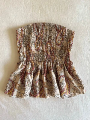 Paisleymönstrad tubtopp - Supersöt smockad tubtopp med volang. Använd fåtal gånger, köpt utomlands