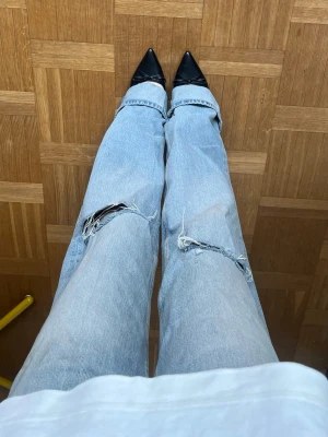 Ljusblå slitna jeans med raka ben - Ljusblå jeans med raka ben och coola slitningar på knäna. Jeansen har klassisk femficksdesign och är tillverkade i denim.